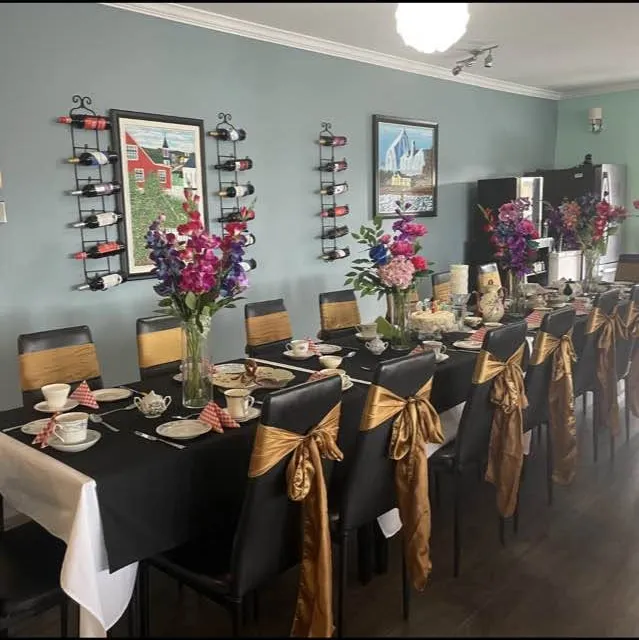 Long dining table at Pier 39 set with black cloths, teacups, gold sashes and flowers